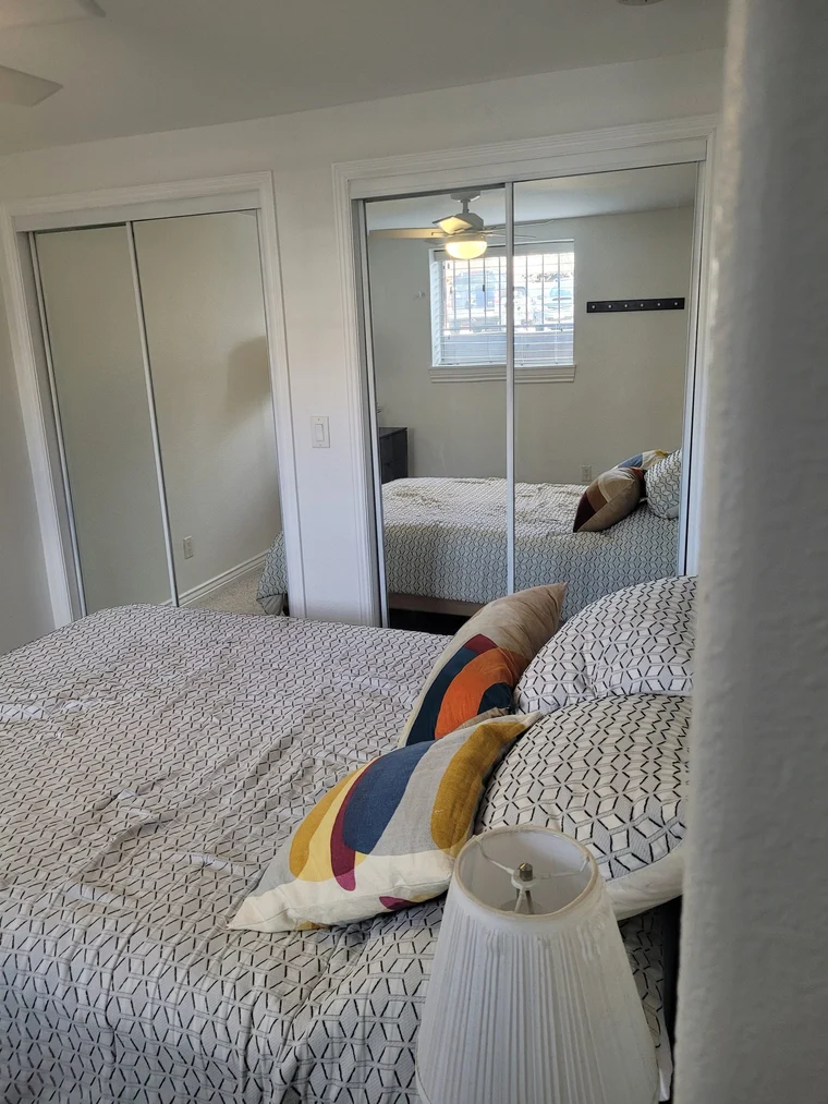 Freshly cleaned bedroom with a made bed and mirrored closet doors