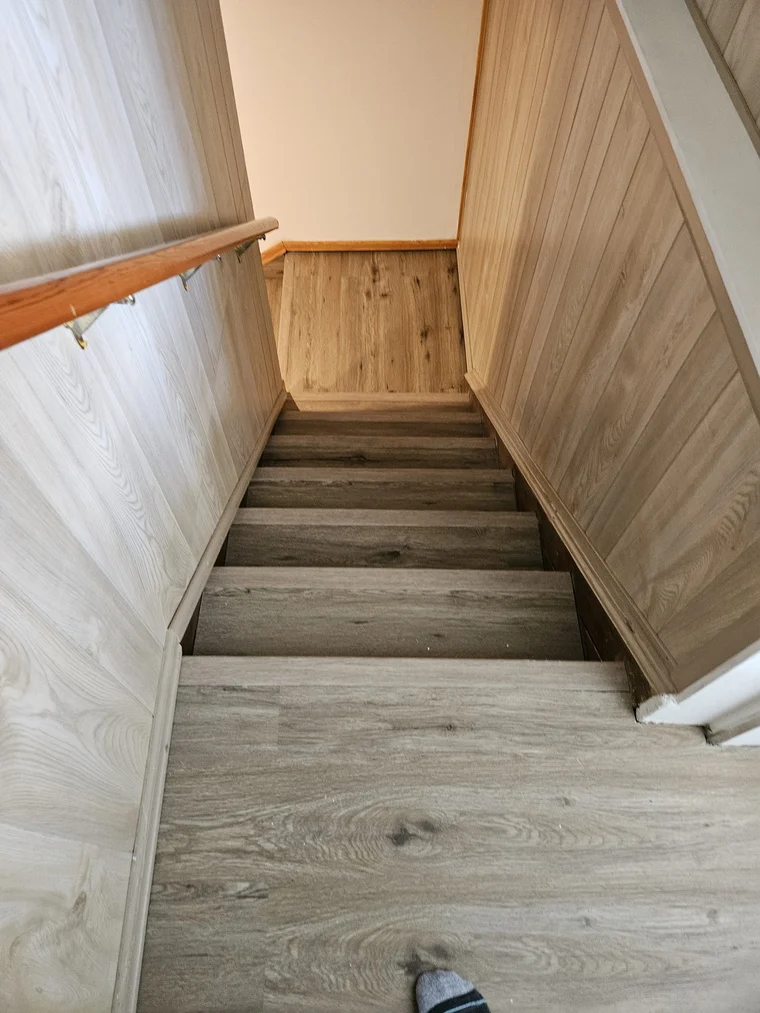 Remodeled staircase with new wood flooring and pine-panelled walls