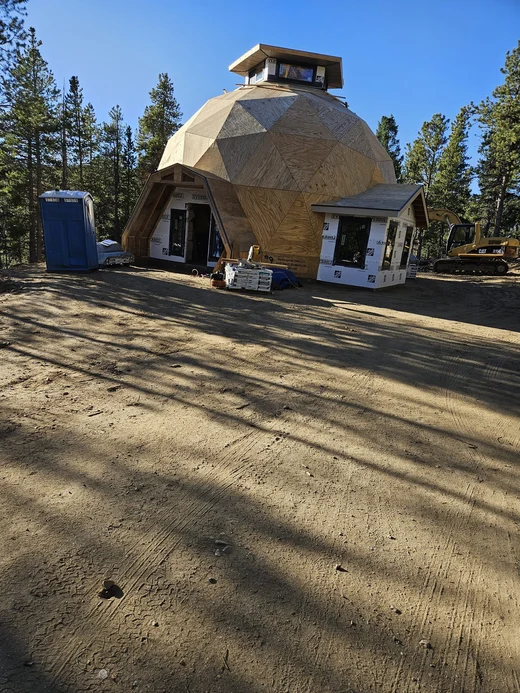 Geodesic dome home with new roofing in a pine forest