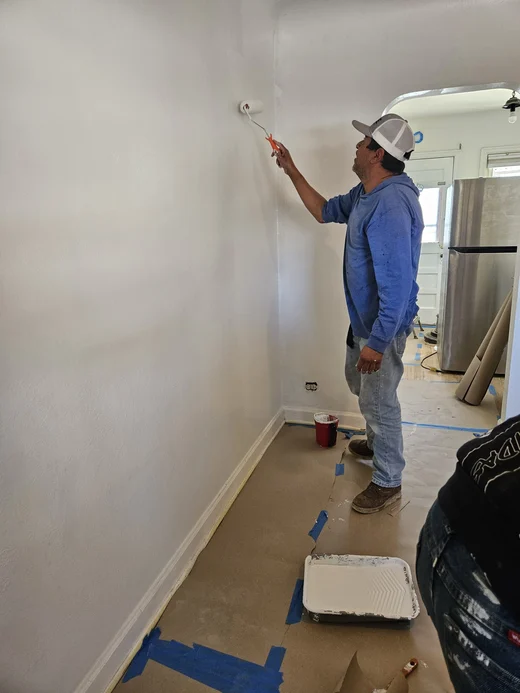 Painter rolling primer onto a white interior wall